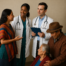 Diverse medical care team consulting with a woman while an older couple receives compassionate attention from a doctor and nurse in a clinical setting.