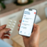 A person holds pills and a phone showing a medication reminder app with today’s medicines and a doctor’s appointment.